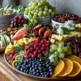 Eine farbenfrohe Obsttafel mit frischen Trauben, Beeren, Melonen und essbaren Blüten – perfekt für eine festliche Abschlussfeier.