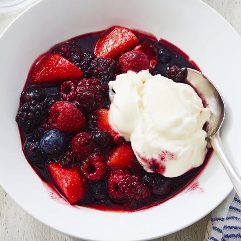 Bunte Mischung aus frischen Beeren, serviert mit cremigem Sahnehäubchen.  