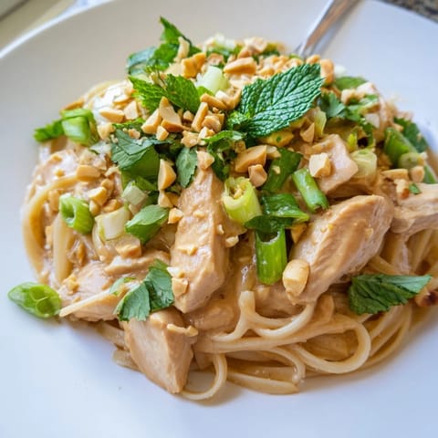A creamy plate of Thai Peanut Chicken Pasta, garnished with fresh herbs and peanuts, ready to eat.