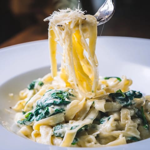Frische Spinatblätter vermengt mit al dente Fettuccine und würziger Knoblauch-Sahne-Sauce.  
