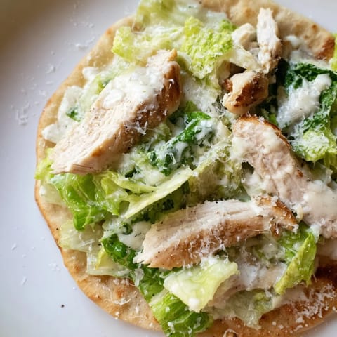 Ein belegtes Fladenbrot mit saftigem Hähnchen, frischer Rucola, Parmesan und würziger Caesar-Dressing-Note, perfekt für einen schnellen Imbiss.