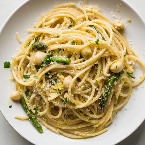 Roasted Garlic & Asparagus Pasta tossed with olive oil and spaghetti, garnished with fresh parsley and grated Parmesan cheese.