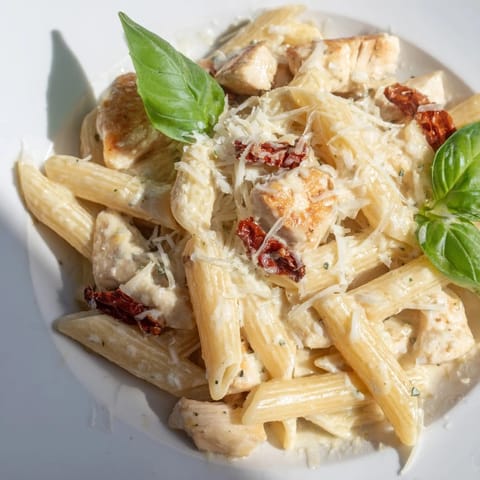 Creamy Sun-Dried Tomato Chicken Pasta served in a bowl with fresh basil and grated Parmesan, glistening in rich sauce.
