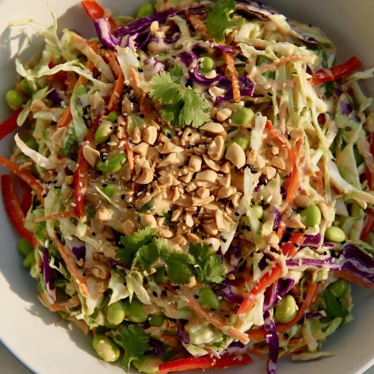 Crunchy Thai Peanut Salad topped with chopped peanuts, sesame seeds, and lime wedges, perfect for a light vegetarian meal.