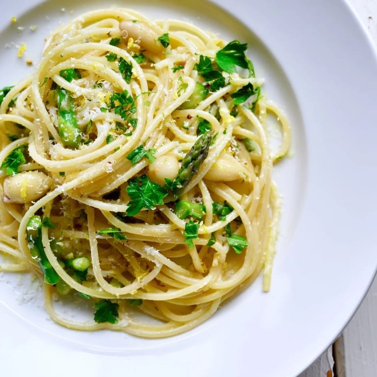 Tender roasted garlic cloves and vibrant green asparagus nestled in a skillet with spaghetti, ready to serve on a spring evening.
