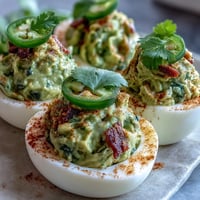 Guacamole gefüllte Deviled Eggs mit frischer Guacamole und rauchigem Paprika-Topping.